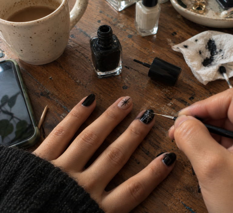 Painting a spider web onto a black nail with a fine brush