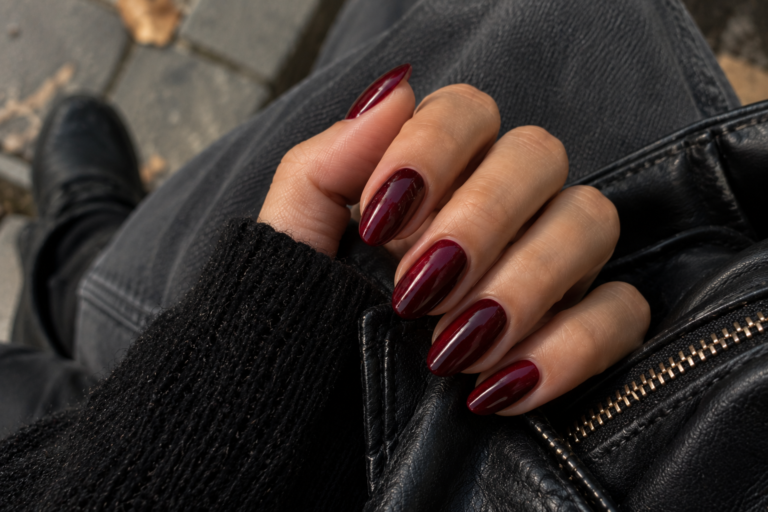 Glossy deep red almond nails against a black leather jacket